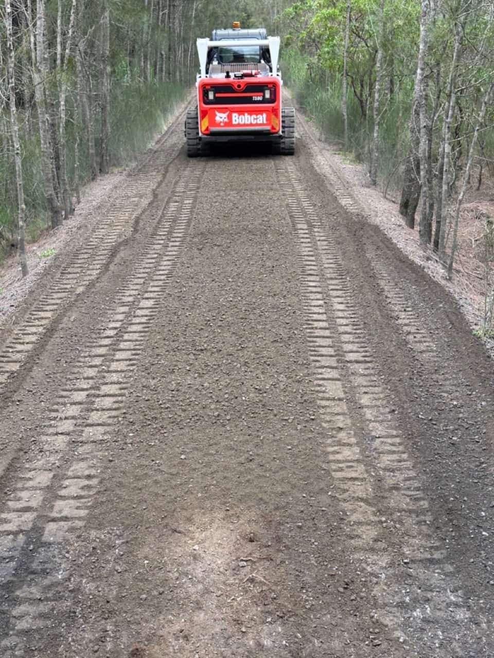 A Bobcat Tractor Driving Down A Dirt Road — Sal's Excavations In Falls Creek, NSW