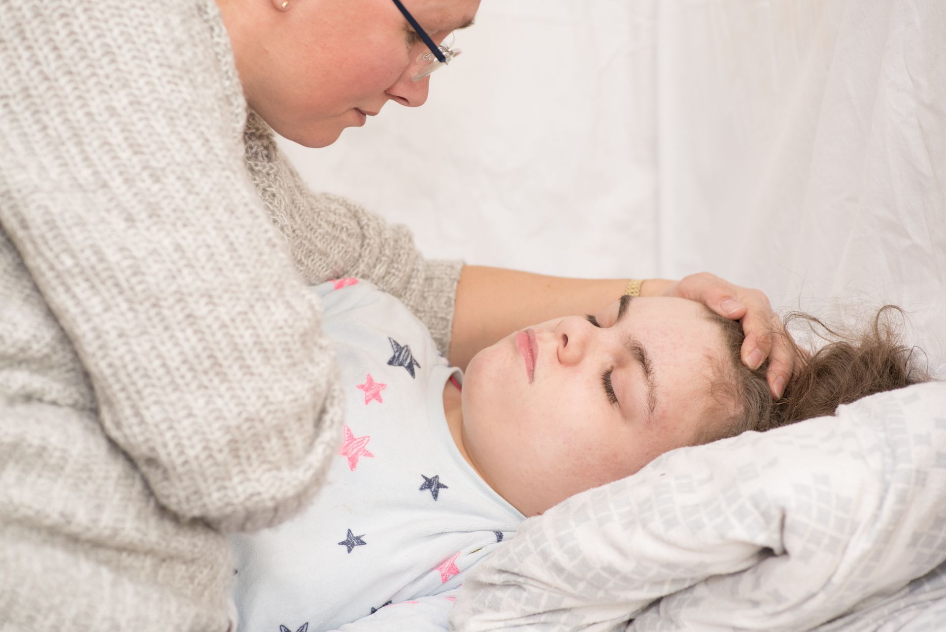 Woman gently touching a resting patient’s forehead in a bright room