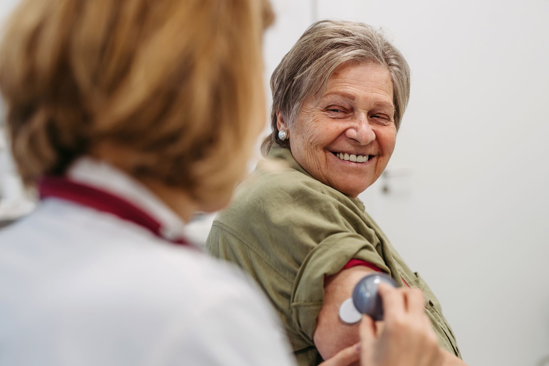 Healthcare worker taking blood pressure of a smiling patient in a clinic