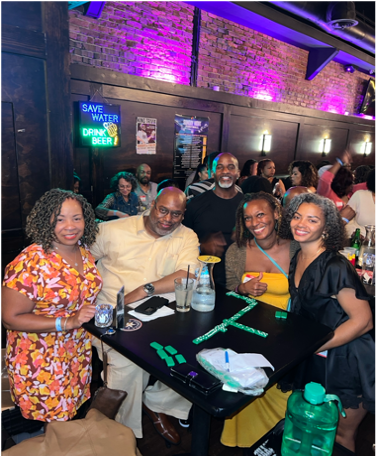 Friends seated at a table in a dimly lit bar with purple lights, smiling for a group photo