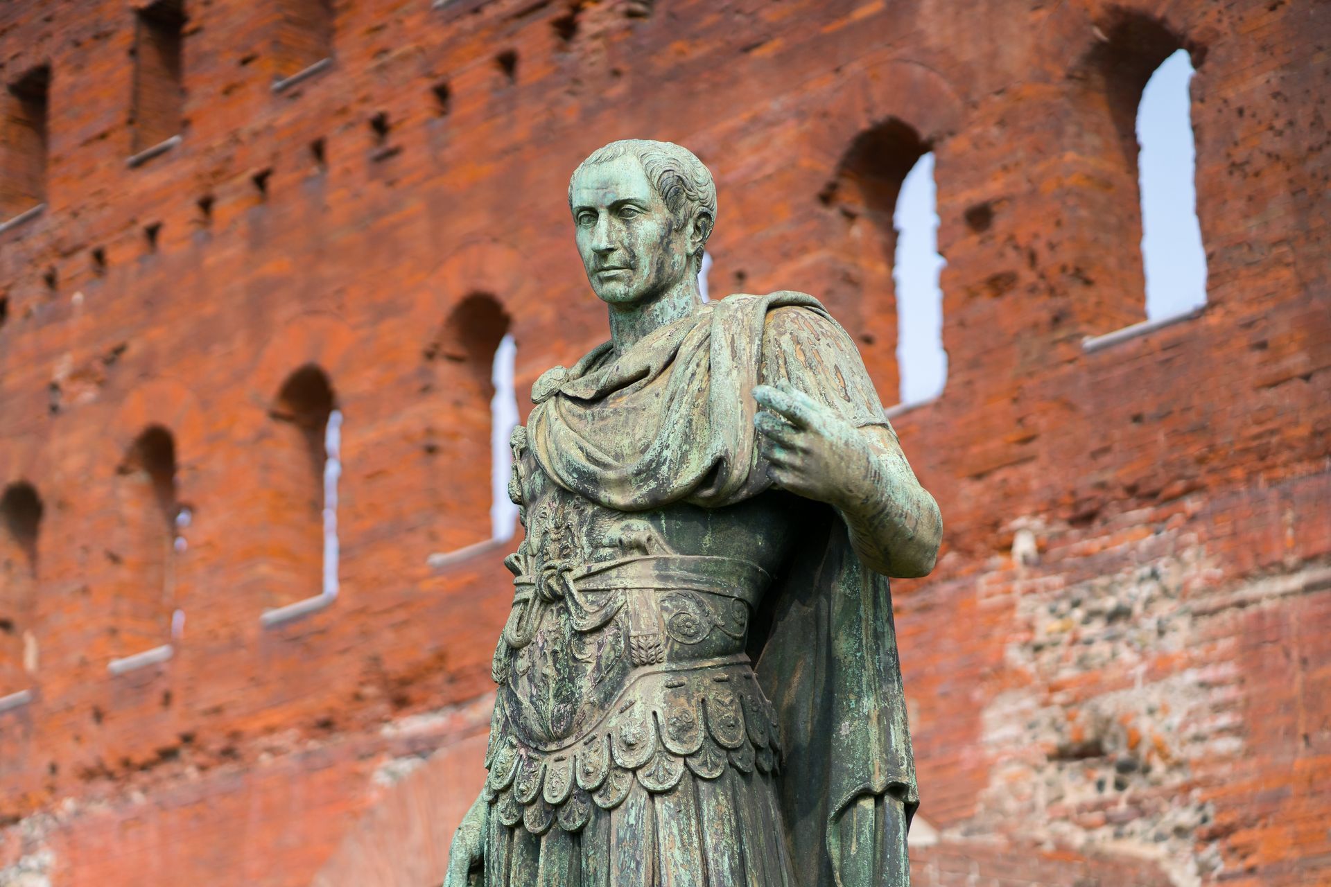 Statue in front of a red brick fortress wall with arched windows