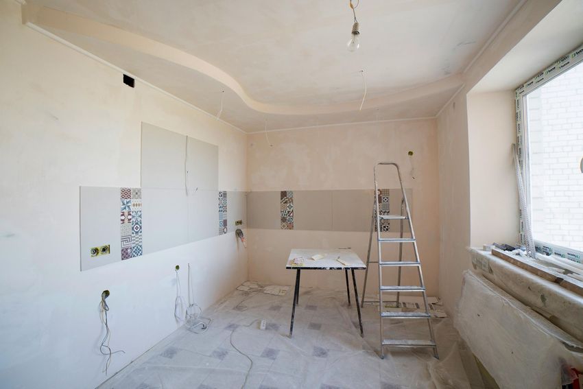 Renovating room with ladder, worktable, and white walls near a large window