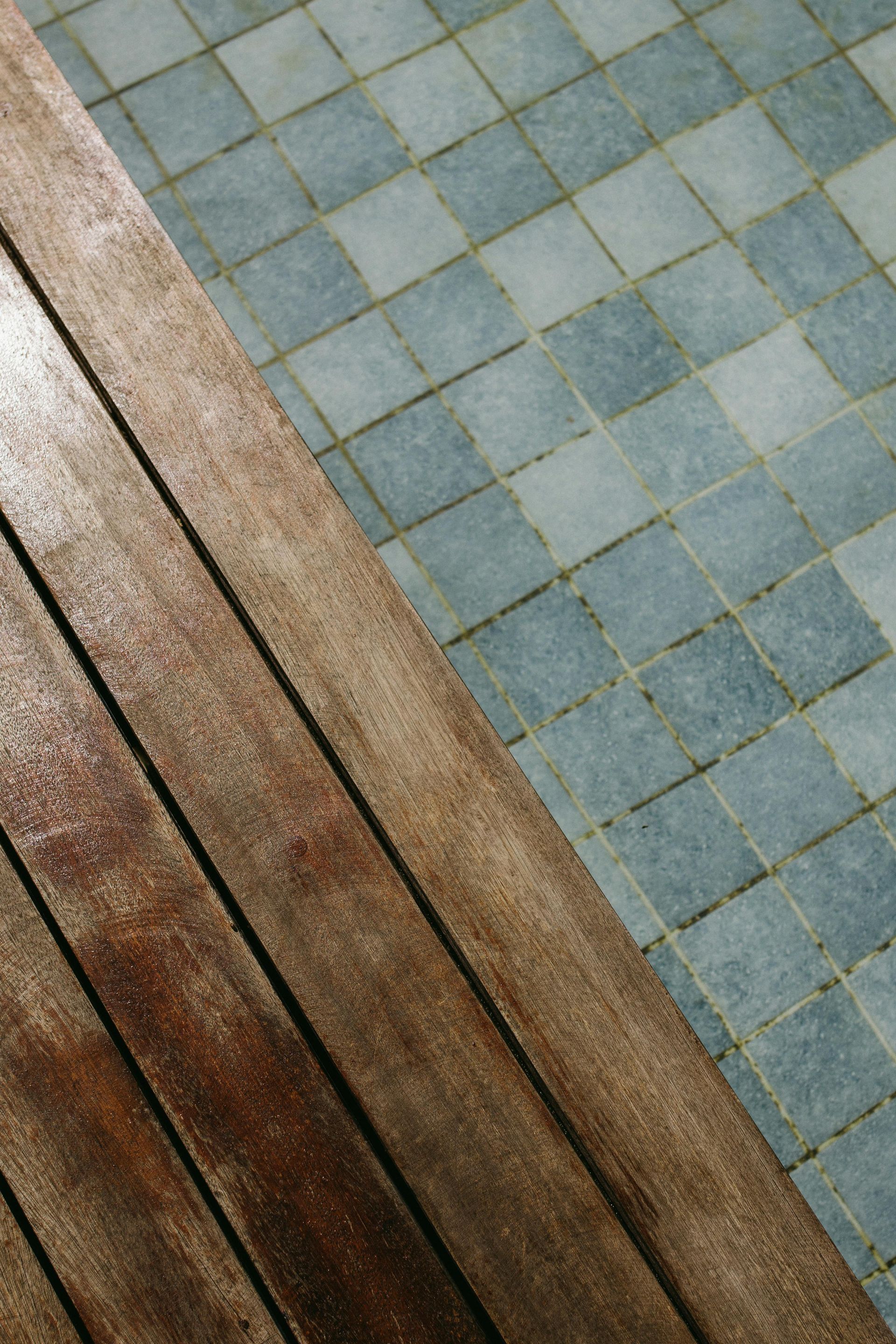 Blue-gray tiled floor beside brown wooden steps, viewed at a diagonal angle