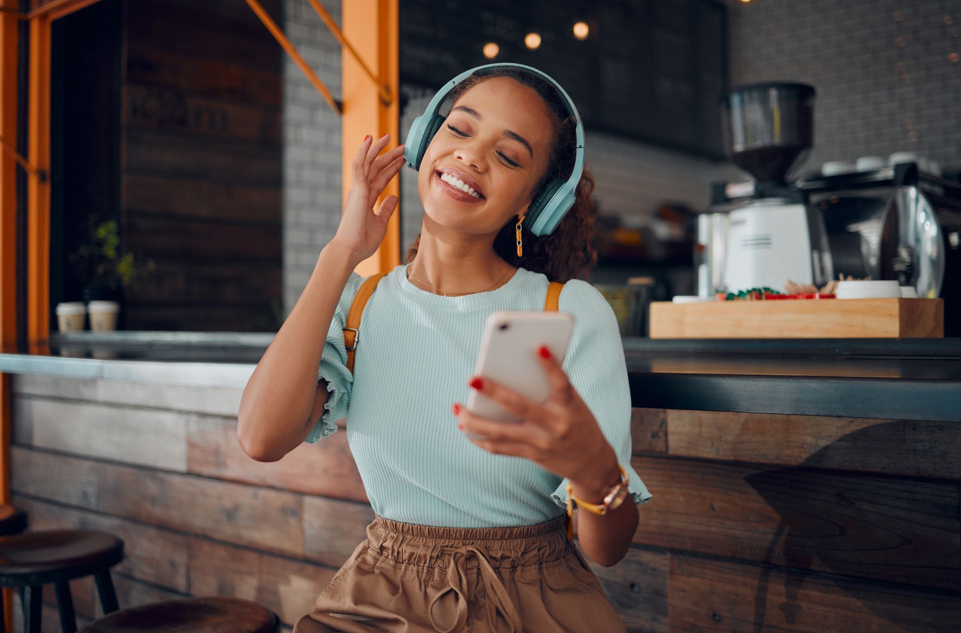 A woman wearing headphones is listening to music on her phone.