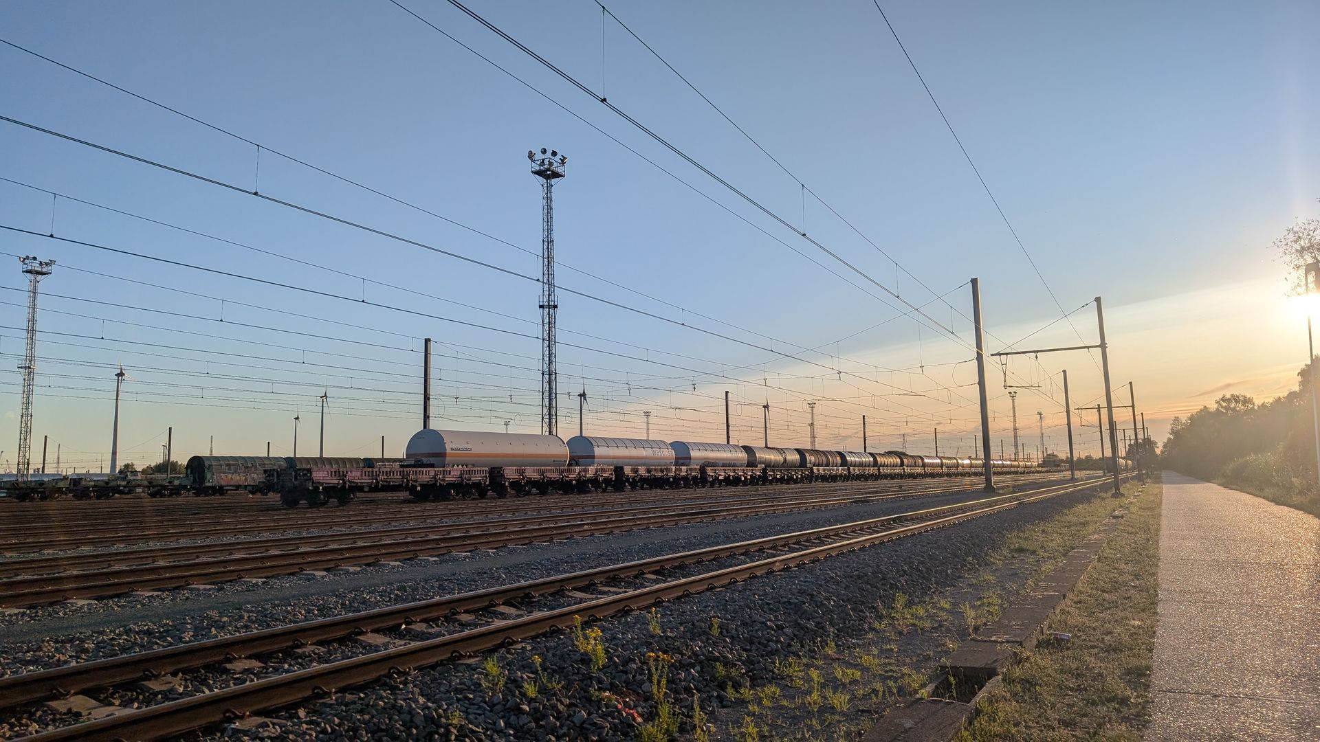Train on tracks with utility poles, set against a sunset sky.