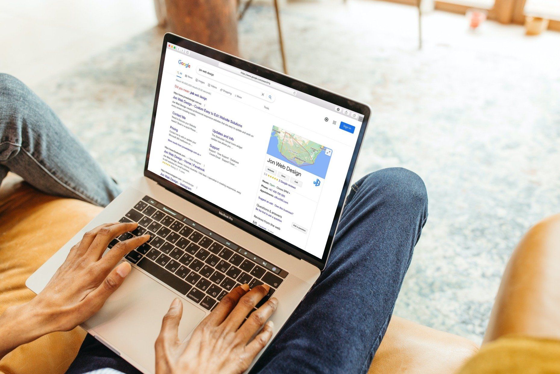 A person is sitting on a couch using a laptop computer.