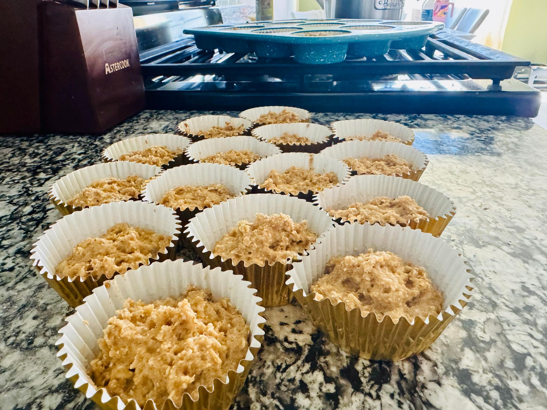 Cupcake liners filled with batter on a countertop, with a baking sheet in the background.