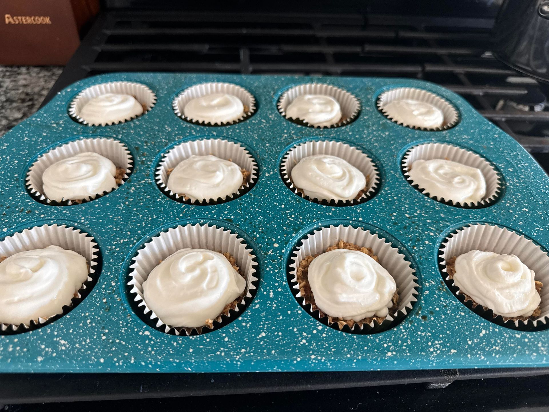A teal muffin tin filled with mini cheesecakes ready to be baked.