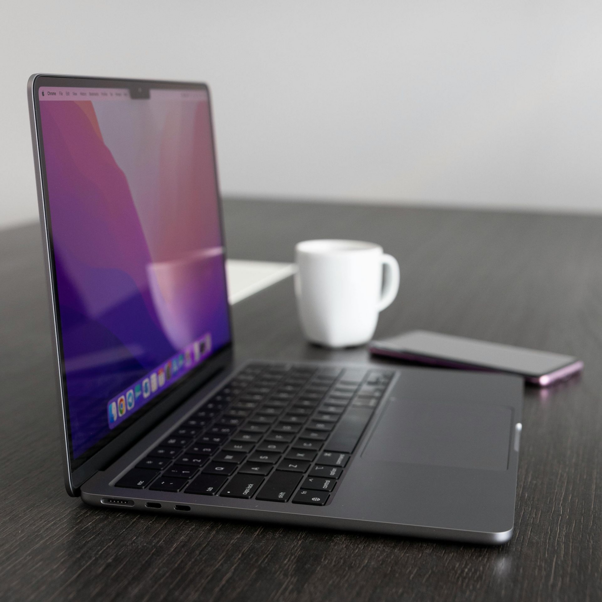 Open laptop on a desk beside a white mug and a smartphone
