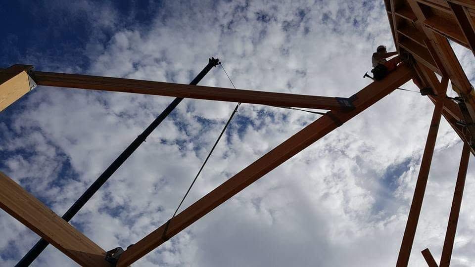 Wooden beams and black cables forming a structure against a cloudy sky