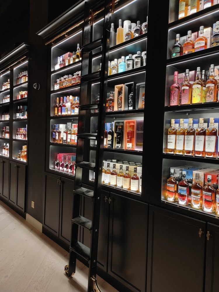 Glass-door liquor display shelves in a modern store aisle, filled with assorted bottles and illuminated inside