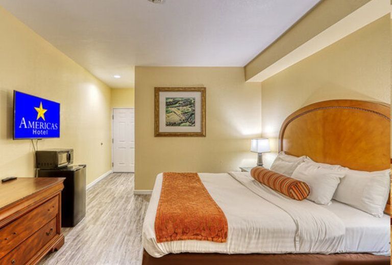 A hotel room with a king size bed and a flat screen tv