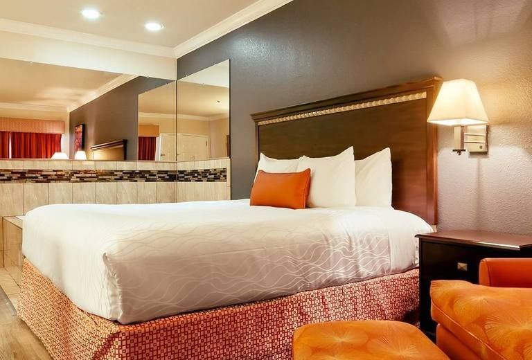 A hotel room with a king size bed and orange chairs