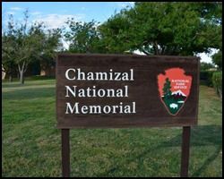 A wooden sign for the chamazal national memorial in a park.
