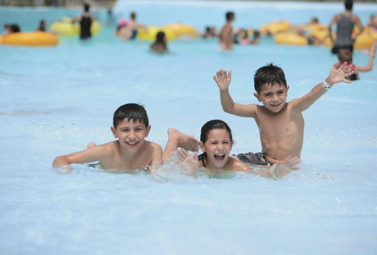 Three children are playing in a swimming pool.