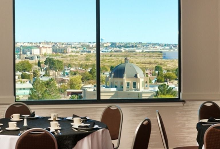 A room with tables and chairs and a large window with a view of a city