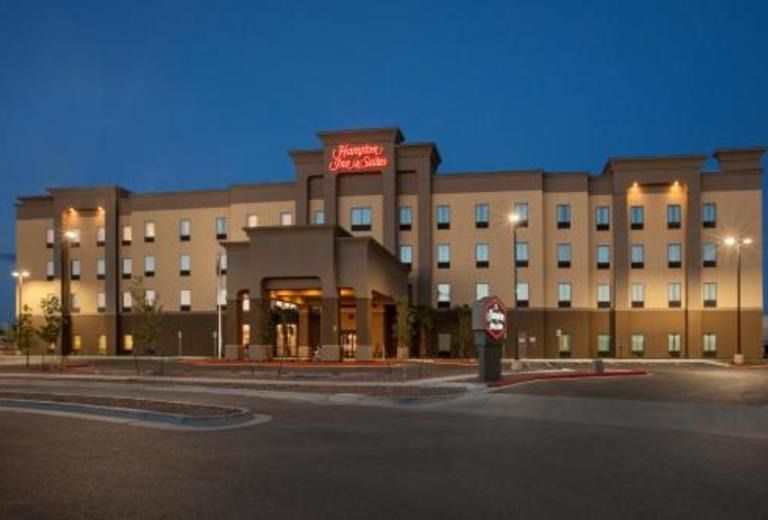 A large hotel with a red sign that says hampton inn & suites