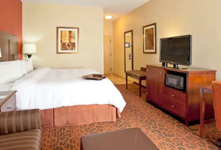 A hotel room with a king size bed and a flat screen tv
