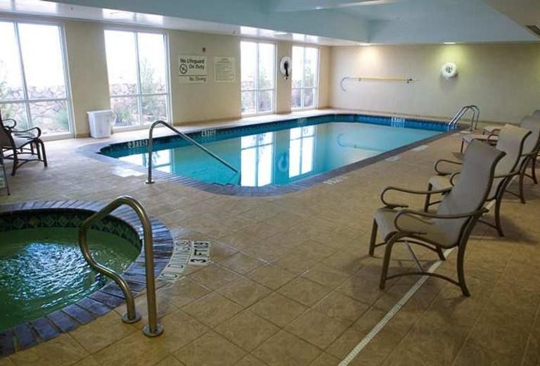 A large indoor swimming pool with chairs and a hot tub.