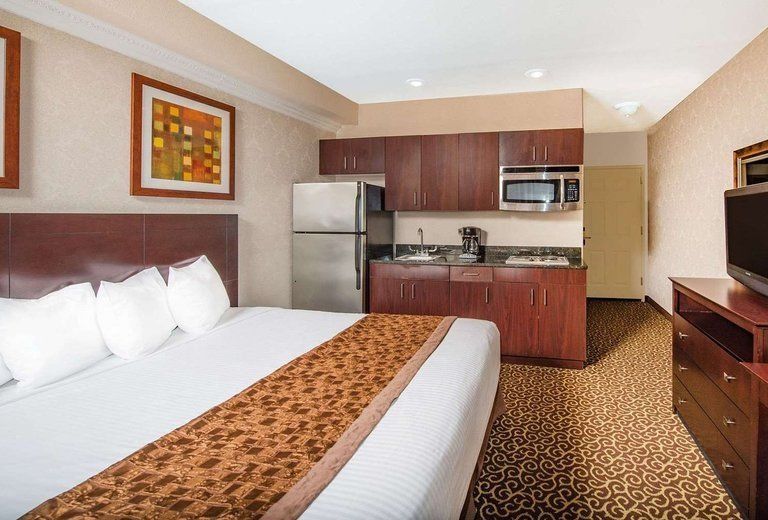 A hotel room with a king size bed and a kitchen
