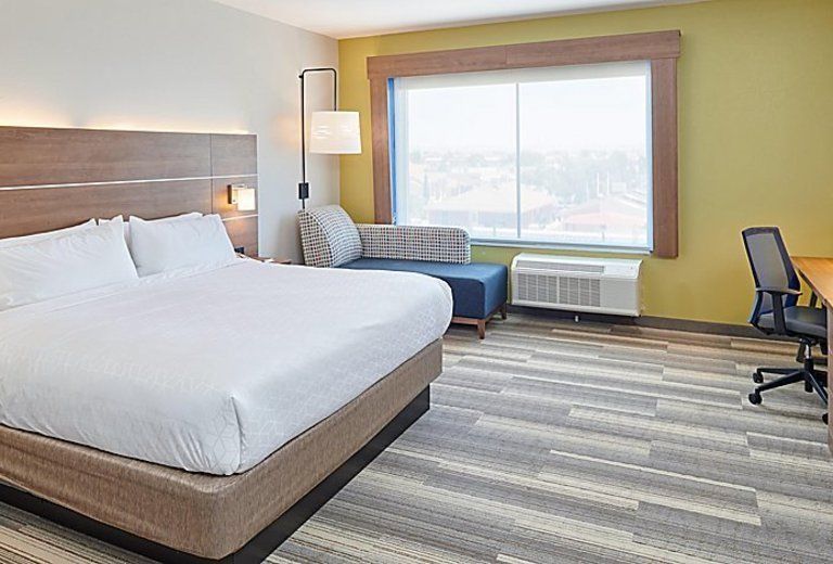 A hotel room with a king size bed , couch , desk and chair.