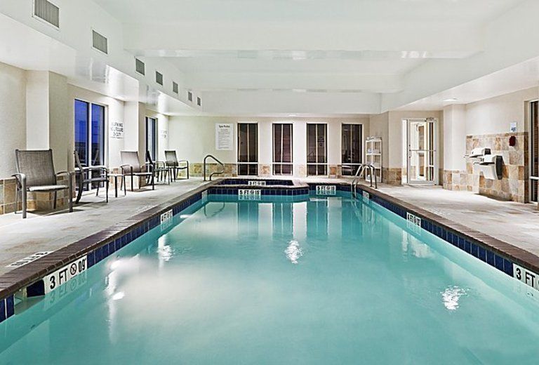 A large indoor swimming pool with chairs and tables around it.