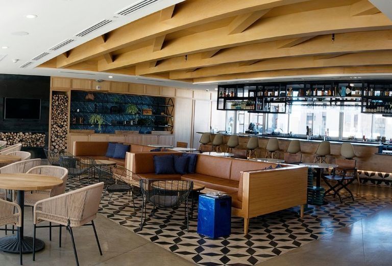 A restaurant with tables , chairs , a couch and a bar.