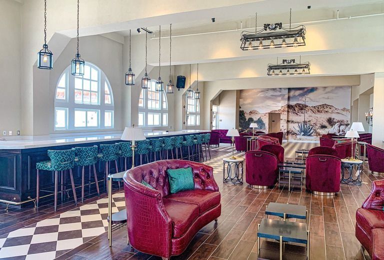 A large room with a couch , chairs , tables and a bar.