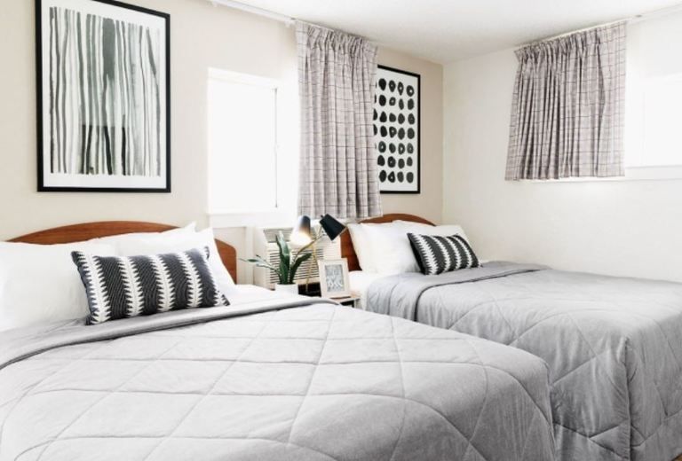 A bedroom with two beds and two pictures on the wall