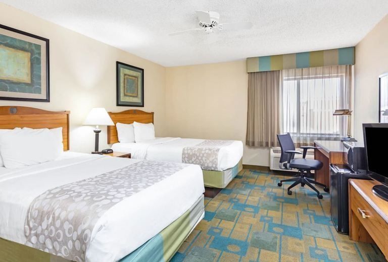 A hotel room with two beds , a desk and a television.