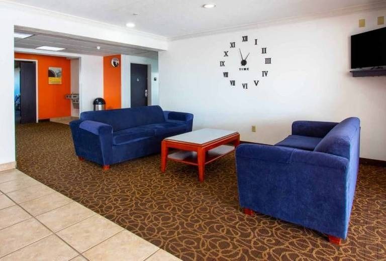 A living room with blue couches and a clock on the wall