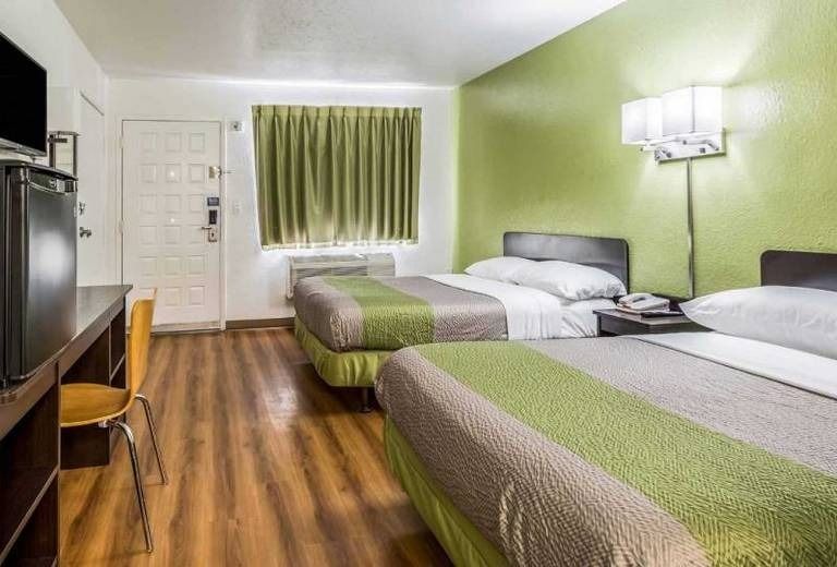 A hotel room with two beds , a desk and a television.