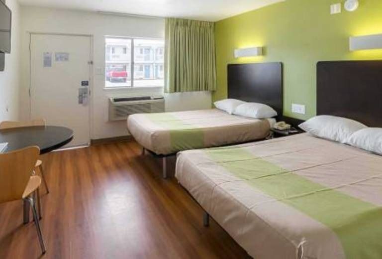 A hotel room with two beds , a table and chairs.