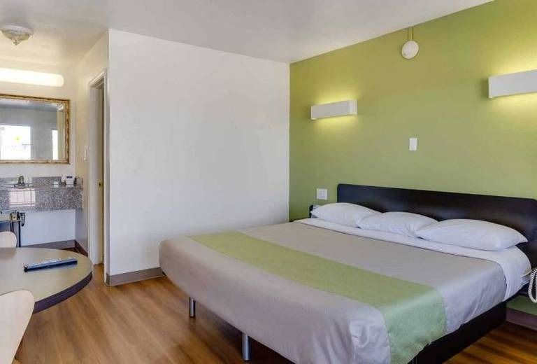 A hotel room with a king size bed and green walls.