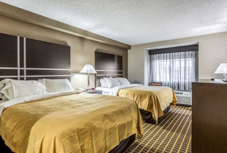 A hotel room with two beds and a window.