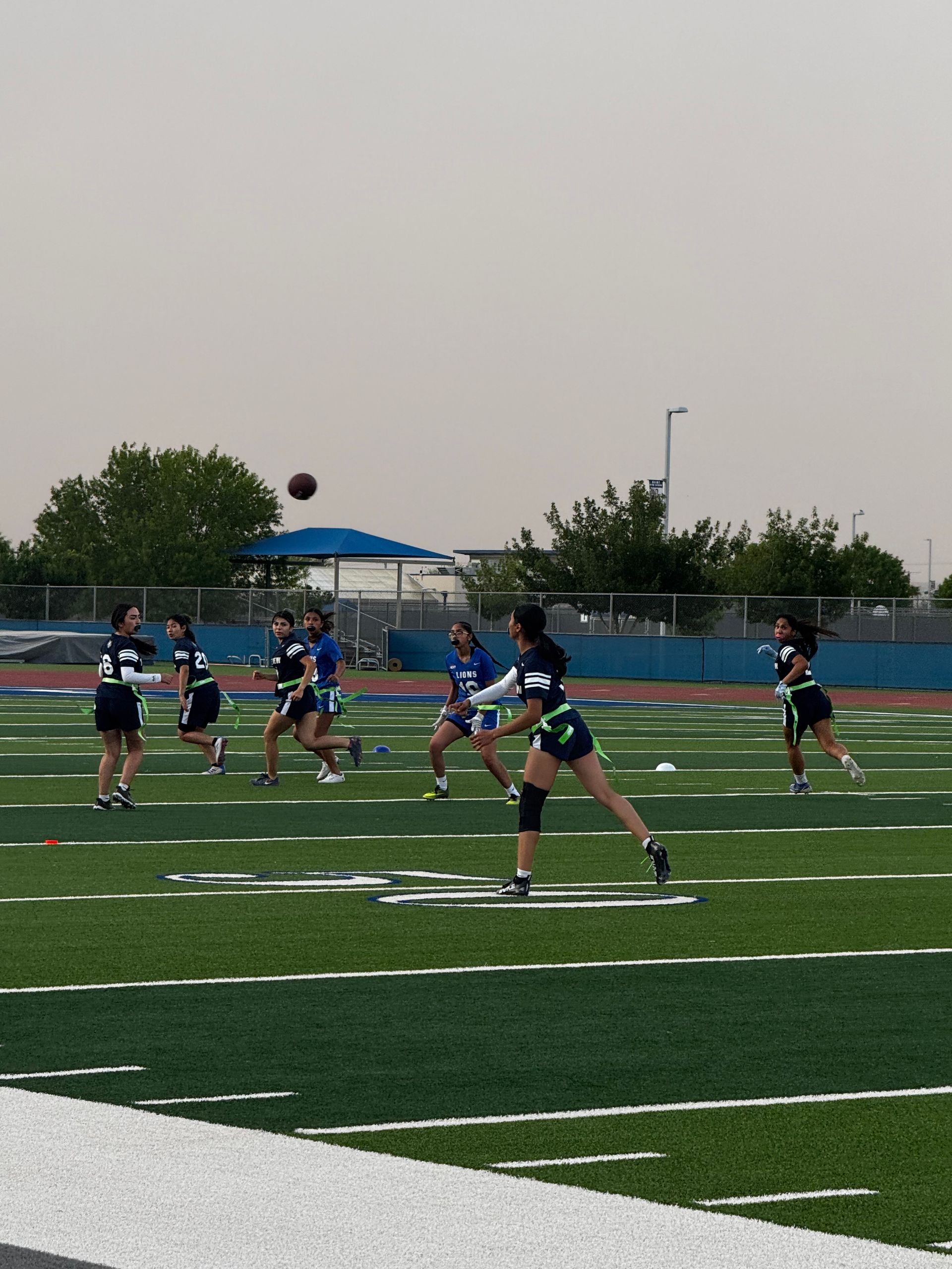 A group of people are playing a game of football on a field.