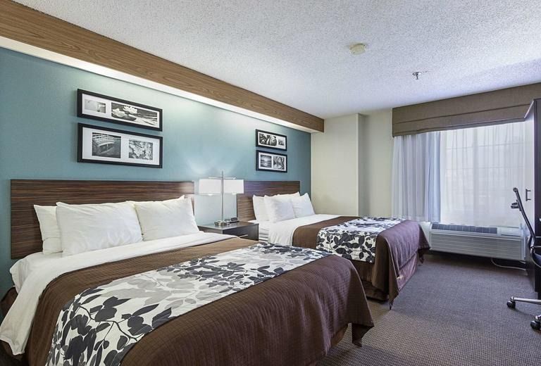 A hotel room with two beds , a desk and a window.