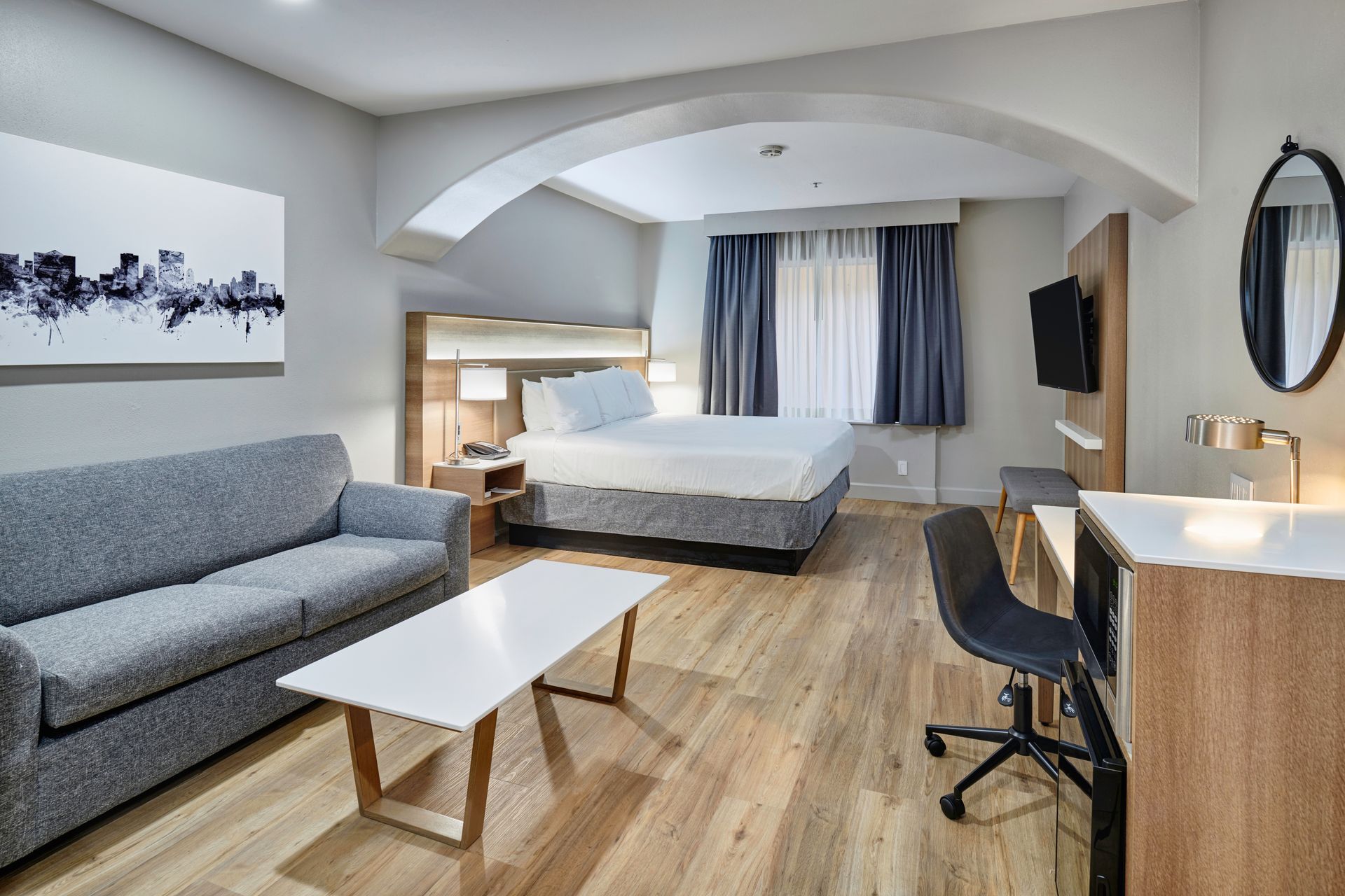 A hotel room with a king size bed , a couch , a coffee table and a desk.