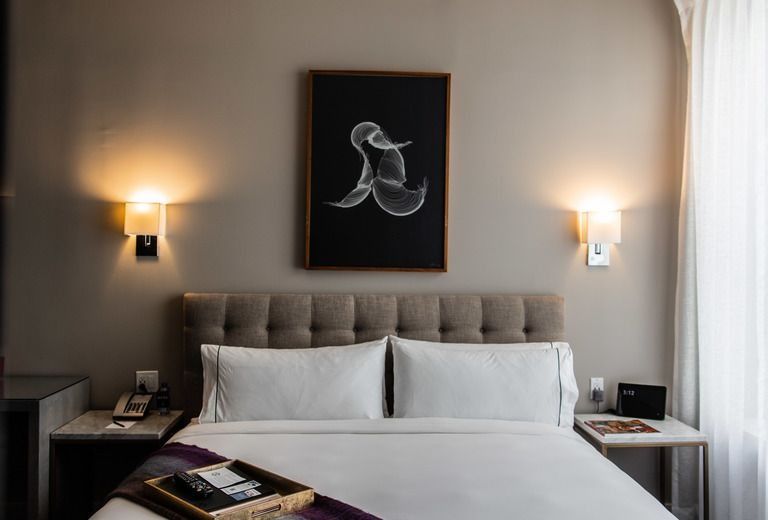 A hotel room with a bed , nightstand , and a painting on the wall.