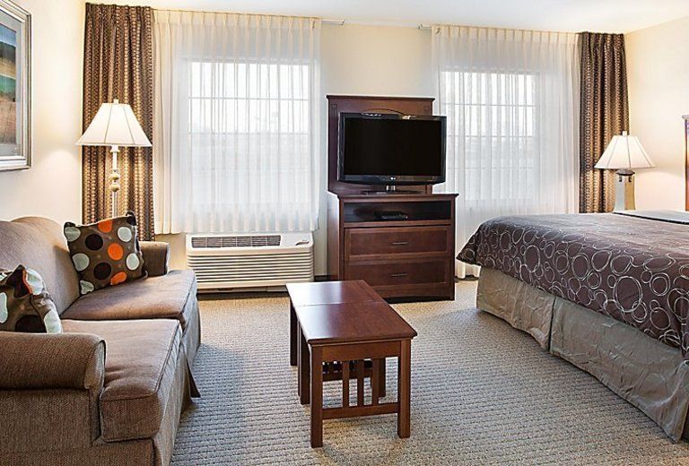A hotel room with a couch , table , television and bed.
