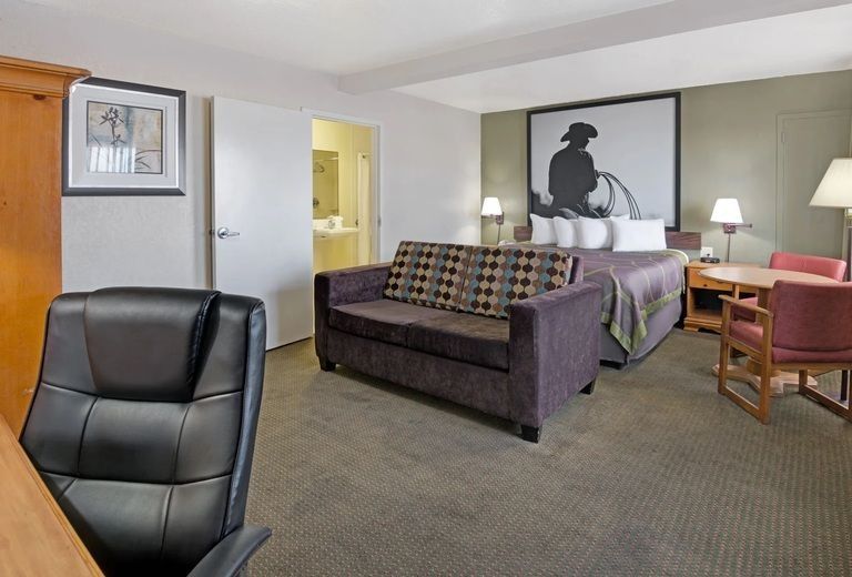A hotel room with a couch , desk , chairs and a bed.