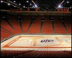 A large empty stadium with a basketball court in the middle of it.