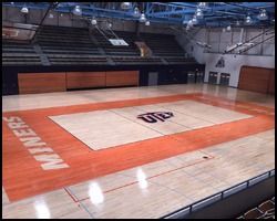 A basketball court in a gym with a logo on the floor.