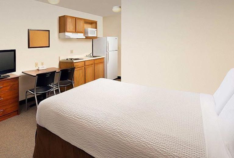 A hotel room with a king size bed and a kitchen.