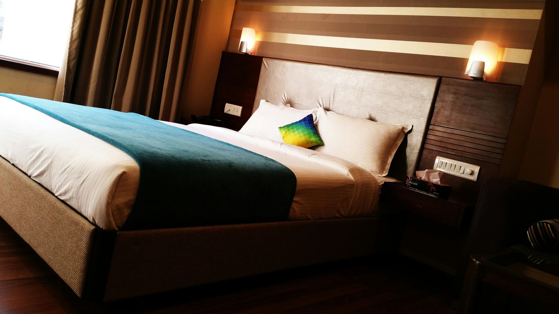 A hotel room with a king size bed and a window.