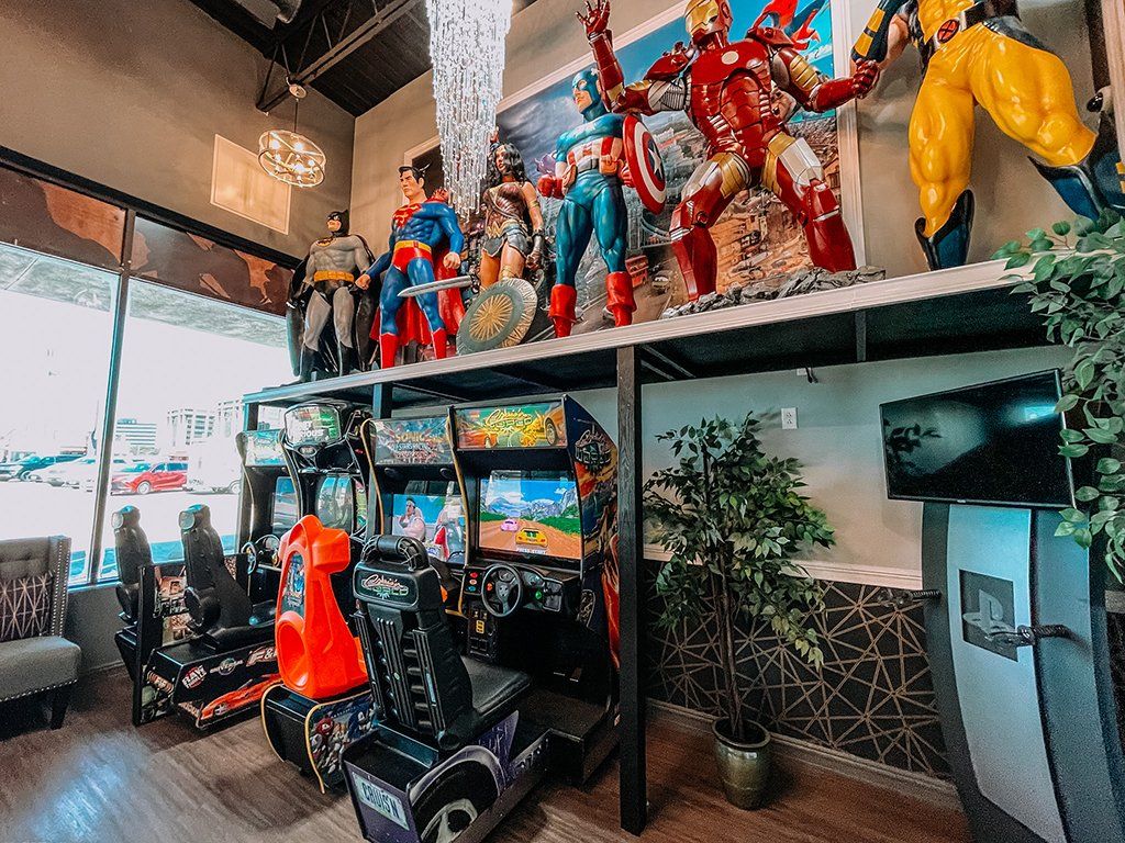 Superhero display in a shop, with life-size figures and collectibles arranged on shelves and a mezzanine.