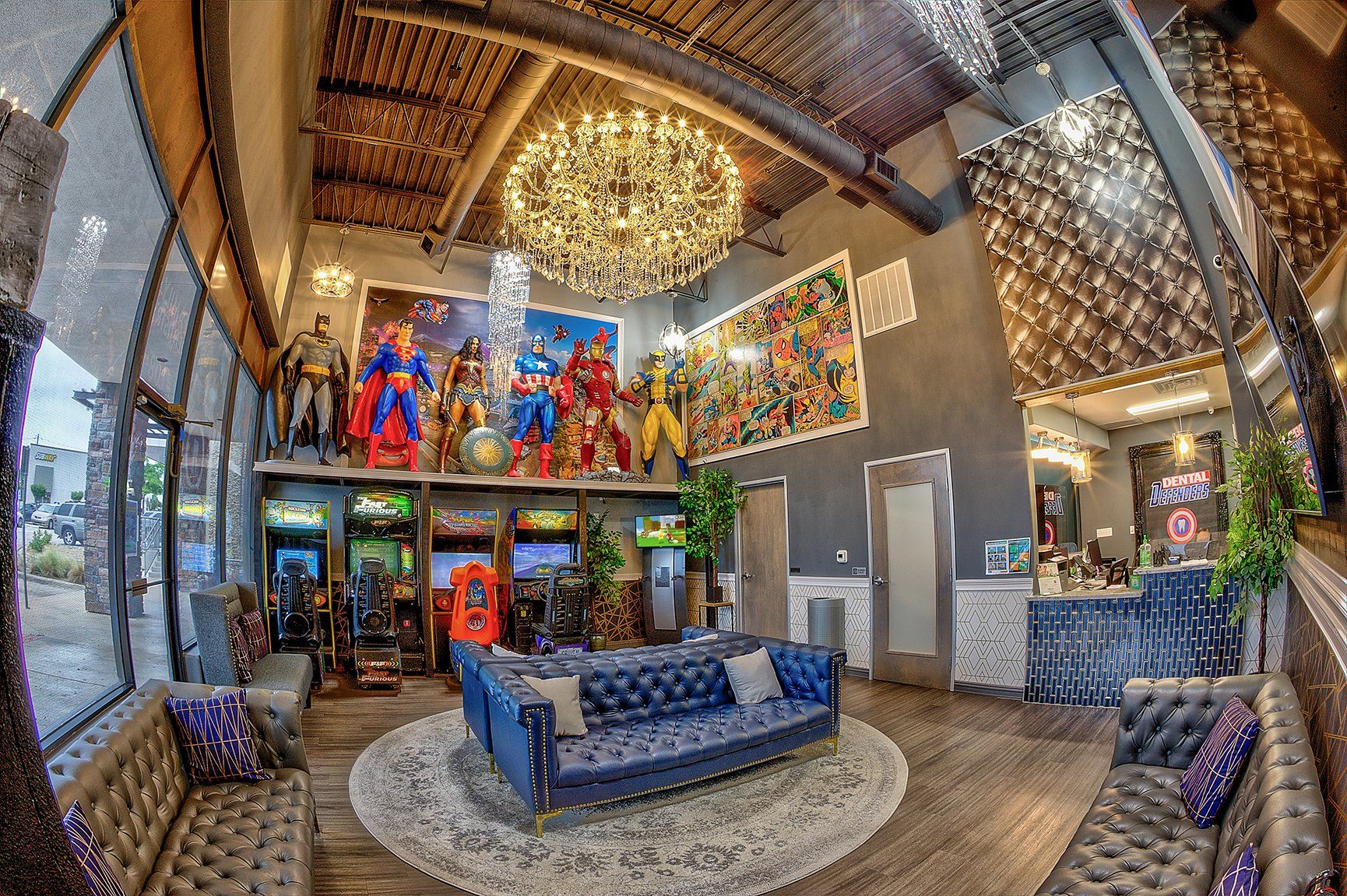 Colorful lobby with blue sofas, large chandelier, and superhero wall art under a high wooden ceiling