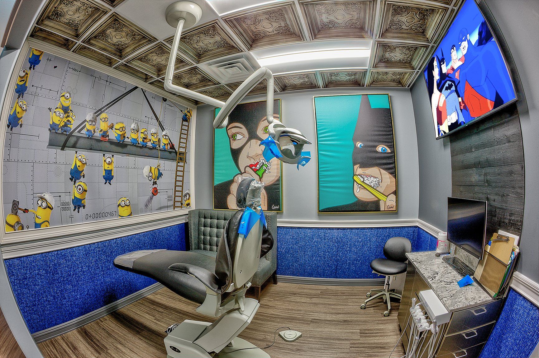 Dentist office with dental chair, overhead lights, wall-mounted TV, and blue-and-gray decor