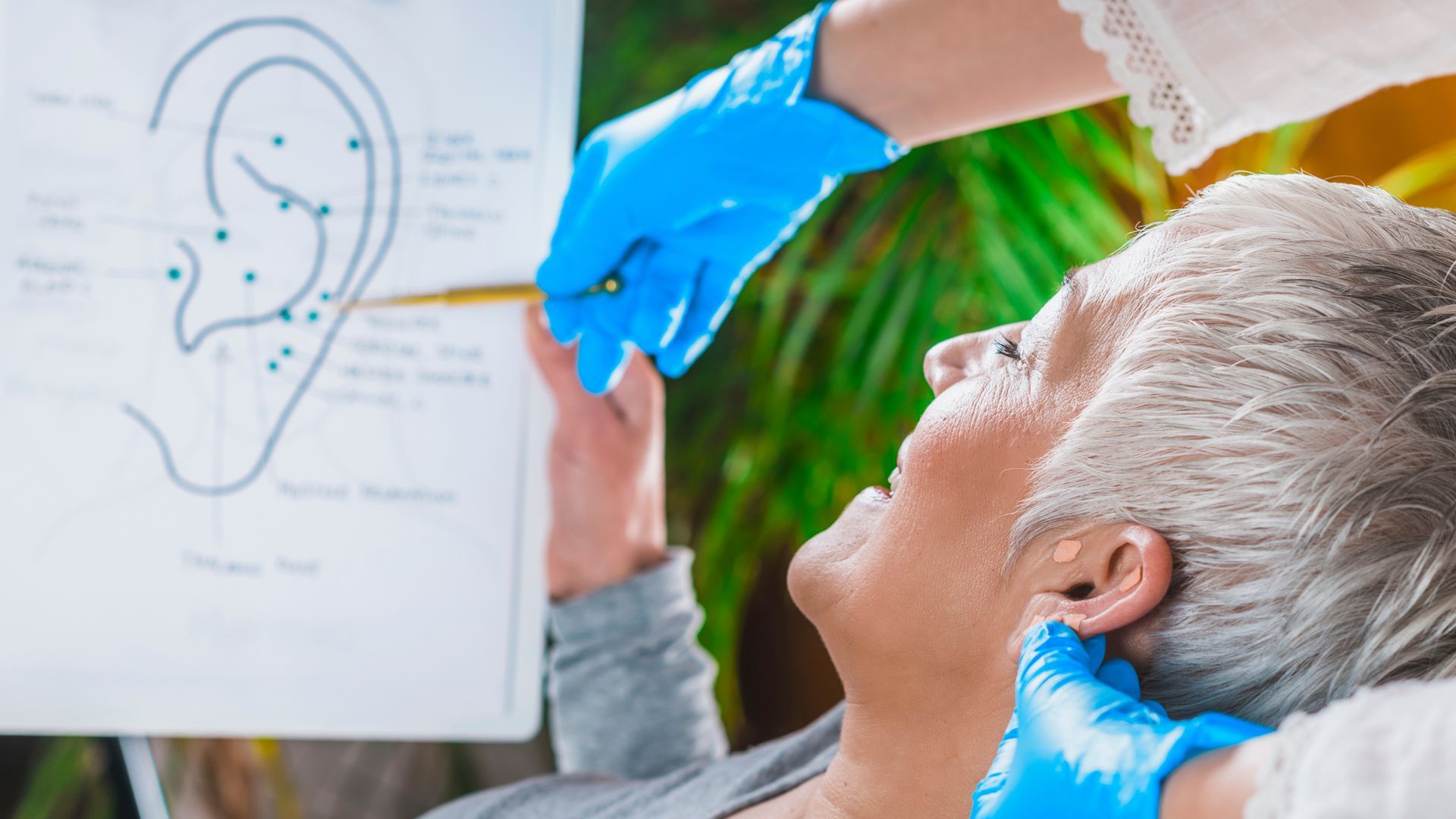 An elderly woman is getting her ears examined by a doctor.