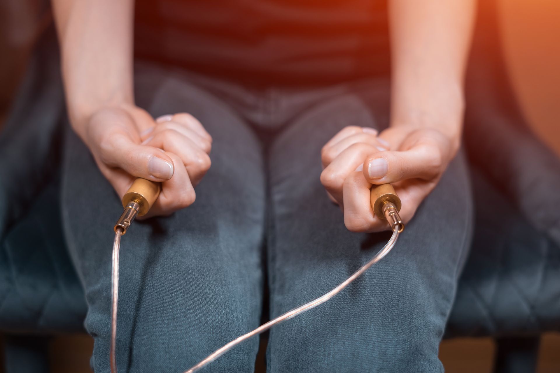 A woman is sitting on a chair holding a jump rope in her hands.